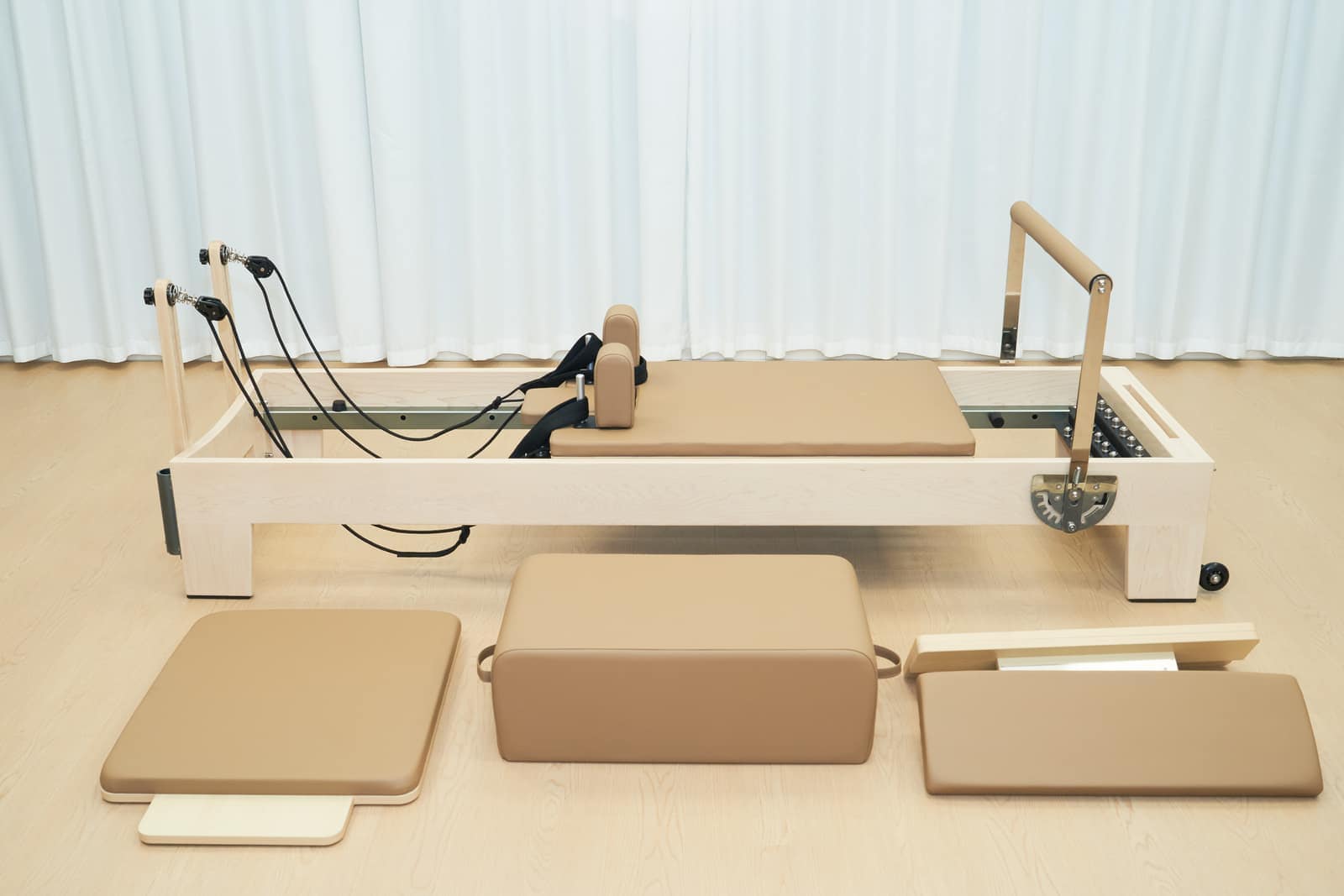Fixed maple Pilates reformer with full-length frame and studio accessories.