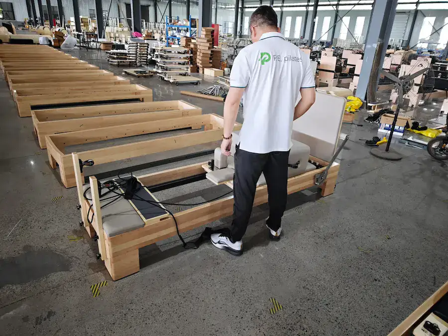P.E.Pilates inspector checking a commercial Pilates reformer in the factory